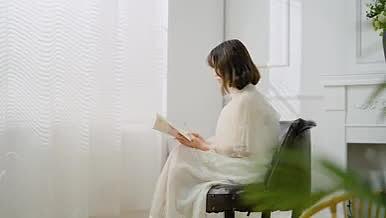 清新文艺女孩在窗前安静读书实拍视频视频的预览图